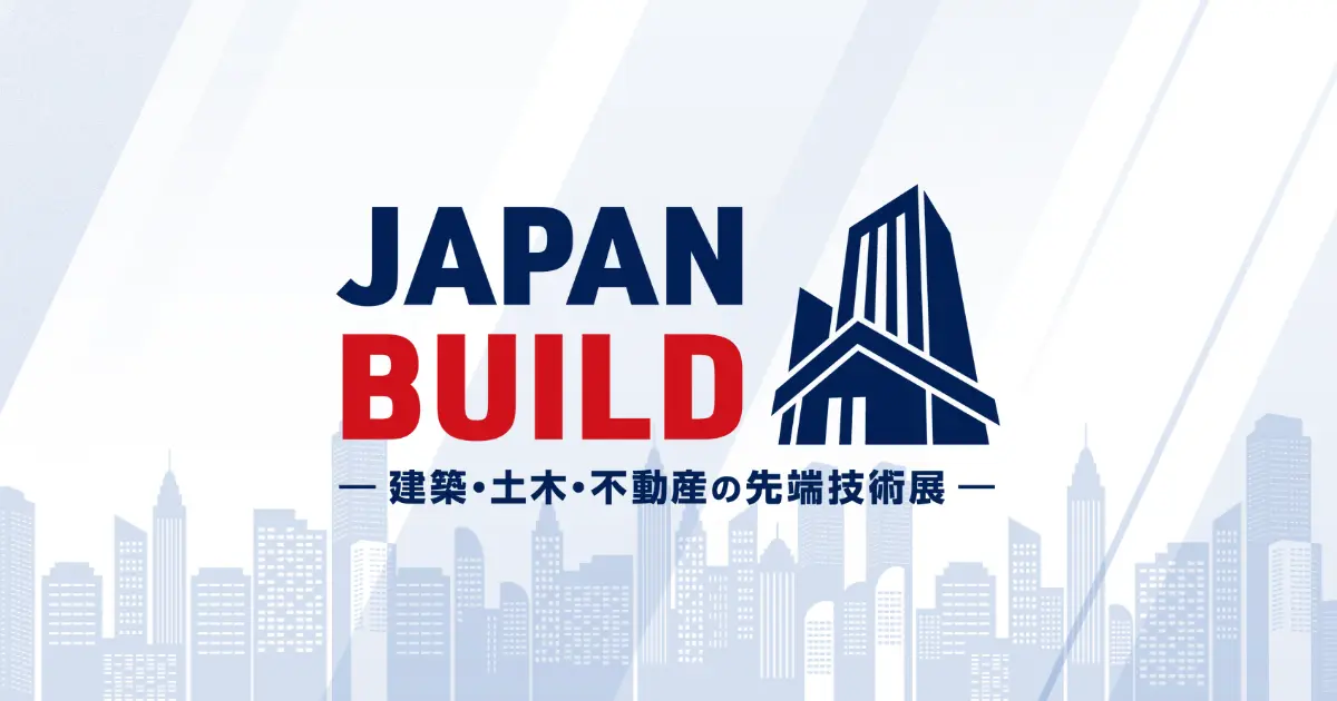 「JAPAN BUILD」のイベントロゴ。中央に「JAPAN BUILD」と書かれており、「JAPAN」は濃い青色、「BUILD」は赤色で強調されています。その下に小さな文字で「— 建築・土木・不動産の先端技術展 —」という説明文が書かれています。右側にはビルをモチーフにした濃い青色のシンボルマークがあります。背景には、薄い灰色と青色のグラデーションで描かれた高層ビルのシルエットが並んでいます。